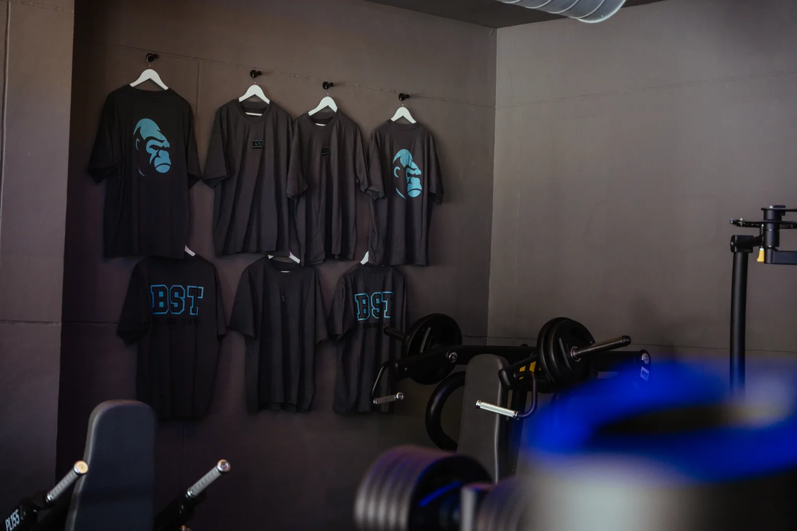 Official black BEAST training shirts displayed on the gym wall